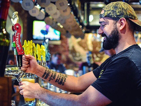 Bartender pouring craft beer at Dogfish Head Alehouse brew pub